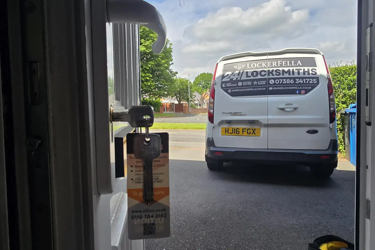 View from a customer's open front doorway looking out to the Lockerfella 24 Hour Locksmiths van parked on the street, the new Ultion key sitting in the door lock in the foreground